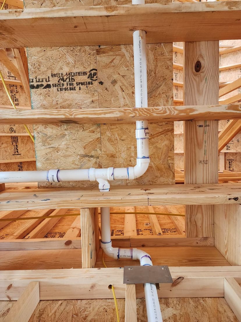 Interior shot of home construction showing PVC plumbing and wooden framing details.